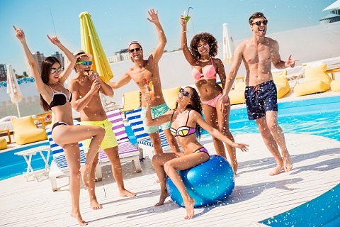 Party all day! Go crazy non stop. Six excited multi national tourists are enjoying at the pool sunny beach disco, with drinks, splashes of water all around! Brunette sit on big ribbon blue ballon (Party all day! Go crazy non stop. Six excited multi na